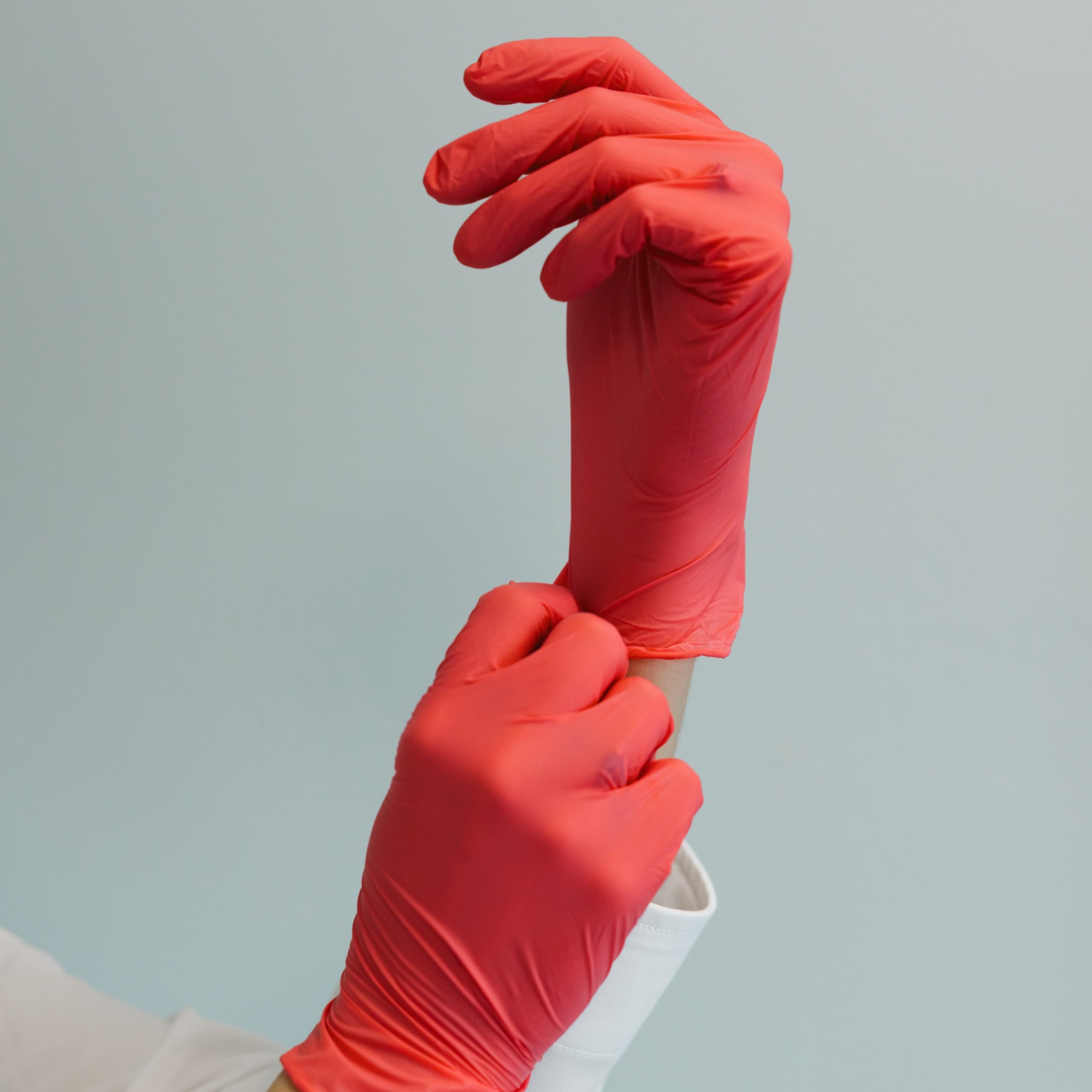 Medical professional putting on red gloves